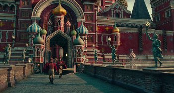 Movie still from “The Nutcracker and the Four Realms” (2018), directed by Joe Johnston – A group of people walking down a street near a building; Wide shot, Low angle