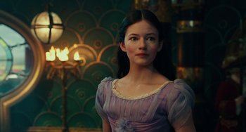 Movie still from “The Nutcracker and the Four Realms” (2018), directed by Joe Johnston – A woman in a purple dress standing in front of a green wall; Close Up shot, Over the shoulder angle