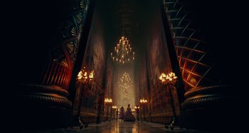 Movie still from “The Nutcracker and the Four Realms” (2018), directed by Joe Johnston – Two people are sitting in a room with chandeliers; Extreme Wide shot, Low angle