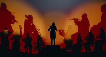 Movie still from “The Nutcracker and the Four Realms” (2018), directed by Joe Johnston – A silhouette of a man standing in front of a group of people; Extreme Wide shot, Low angle