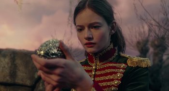 Movie still from “The Nutcracker and the Four Realms” (2018), directed by Joe Johnston – A woman in a military uniform holding a ball; Close Up shot, Over the shoulder angle