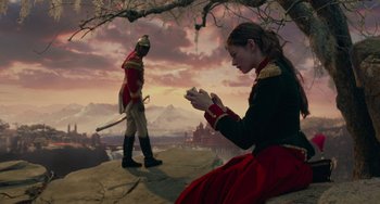 Movie still from “The Nutcracker and the Four Realms” (2018), directed by Joe Johnston – A woman sitting on the ground in front of a man in a uniform; Wide shot, Low angle