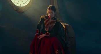 Movie still from “The Nutcracker and the Four Realms” (2018), directed by Joe Johnston – A woman dressed in military clothing sitting in a chair; Medium shot, Low angle