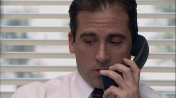 Movie still from “The Office” (2005), created by Ricky Gervais – A person talking on a cell phone; Close Up shot, High angle