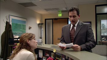 Movie still from “The Office” (2005), created by Ricky Gervais – A man in a business suit is talking to a woman in an office setting; Medium shot, Over the shoulder angle