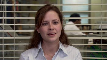 Movie still from “The Office” (2005), created by Ricky Gervais – A woman in a white dress shirt is looking at the camera; Close Up shot, Over the shoulder angle