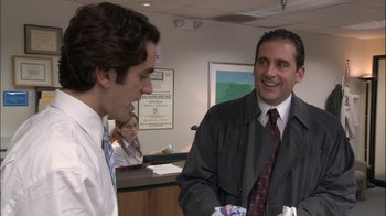 Movie still from “The Office” (2005), created by Ricky Gervais – Two men talking to each other in an office setting; Medium shot, Over the shoulder angle