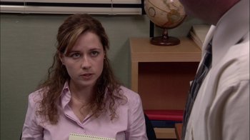 Movie still from “The Office” (2005), created by Ricky Gervais – A woman sitting in front of a globe in a room; Close Up shot, Over the shoulder angle