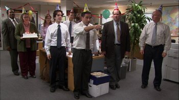 Movie still from “The Office” (2005), created by Ricky Gervais – A group of people standing in an office wearing party hats; Wide shot, High angle