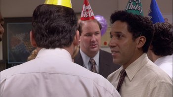 Movie still from “The Office” (2005), created by Ricky Gervais – A group of men standing next to each other wearing party hats; Medium shot, Over the shoulder angle