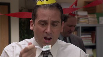 Movie still from “The Office” (2005), created by Ricky Gervais – A person wearing a party hat and holding a spoon; Close Up shot, High angle