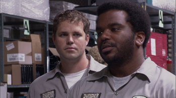 Movie still from “The Office” (2005), created by Ricky Gervais – A couple of men standing next to each other in a warehouse; Close Up shot, Low angle