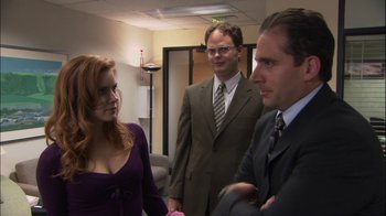 Movie still from “The Office” (2005), created by Ricky Gervais – A woman and two men standing in an office room; Medium shot, Over the shoulder angle