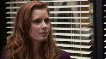 Movie still from “The Office” (2005), created by Ricky Gervais – A beautiful young woman with long red hair and wearing a purple shirt; Close Up shot, Over the shoulder angle