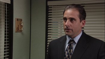 Movie still from “The Office” (2005), created by Ricky Gervais – A person wearing a suit and tie; Medium shot, Over the shoulder angle