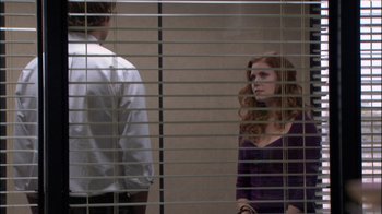 Movie still from “The Office” (2005), created by Ricky Gervais – A man and a woman standing in front of a window; Wide shot, Over the shoulder angle