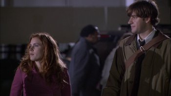 Movie still from “The Office” (2005), created by Ricky Gervais – A man and a woman standing next to each other; Medium shot, Over the shoulder angle