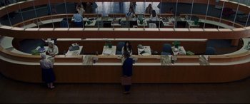 Movie still from “The Old Man & the Gun” (2018), directed by David Lowery – A woman standing in front of a counter in a room; Extreme Wide shot, High angle