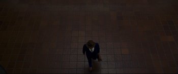 Movie still from “The Old Man & the Gun” (2018), directed by David Lowery – A person crouching on the ground in a room with tiled floors; Extreme Wide shot, Overhead angle