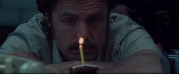 Movie still from “The Old Man & the Gun” (2018), directed by David Lowery – A man is holding a lit candle in his mouth; Close Up shot, Low angle