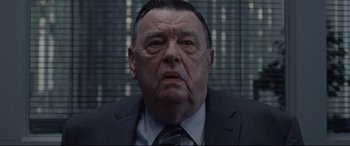 Movie still from “The Old Man & the Gun” (2018), directed by David Lowery – An older man wearing a suit and tie in front of a window; Close Up shot, Low angle