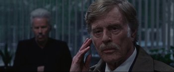 Movie still from “The Old Man & the Gun” (2018), directed by David Lowery – An older man with a beard and mustache is holding his hand up to his ear; Close Up shot, Over the shoulder angle