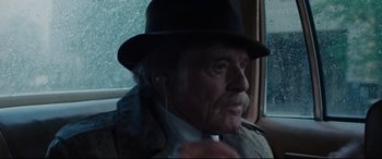 Movie still from “The Old Man & the Gun” (2018), directed by David Lowery – An older man wearing a hat and ear buds; Close Up shot, Over the shoulder angle