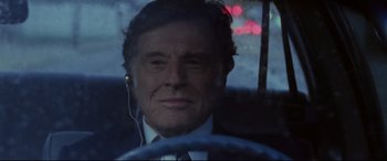 Movie still from “The Old Man & the Gun” (2018), directed by David Lowery – A person in a car wearing headphones; Close Up shot, Over the shoulder angle