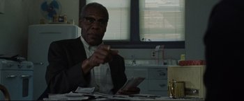 Movie still from “The Old Man & the Gun” (2018), directed by David Lowery – An older man sitting at a table with a bunch of money; Medium shot, Over the shoulder angle