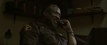 Movie still from “The Old Man & the Gun” (2018), directed by David Lowery – An older man talking on a phone while wearing a uniform; Close Up shot, Low angle