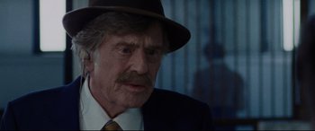 Movie still from “The Old Man & the Gun” (2018), directed by David Lowery – An older man wearing a hat and a tie; Close Up shot, Over the shoulder angle