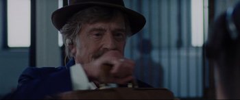 Movie still from “The Old Man & the Gun” (2018), directed by David Lowery – An old man in a hat is holding a cigar; Close Up shot, Over the shoulder angle