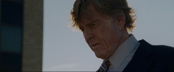 Movie still from “The Old Man & the Gun” (2018), directed by David Lowery – An older man in a suit and tie looking down; Close Up shot, Low angle