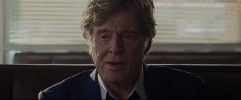 Movie still from “The Old Man & the Gun” (2018), directed by David Lowery – An older man in a suit and tie looking at the camera; Close Up shot, Over the shoulder angle