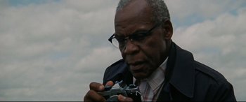 Movie still from “The Old Man & the Gun” (2018), directed by David Lowery – An older man holding a camera in front of a cloudy sky; Close Up shot, Low angle