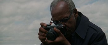 Movie still from “The Old Man & the Gun” (2018), directed by David Lowery – An older man taking a picture with a camera; Close Up shot, Low angle