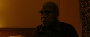 Movie still from “The Old Man & the Gun” (2018), directed by David Lowery – An older man wearing glasses looking at the camera; Close Up shot, Low angle