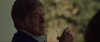 Movie still from “The Old Man & the Gun” (2018), directed by David Lowery – An older man holding a glass in his hand; Close Up shot, Over the shoulder angle