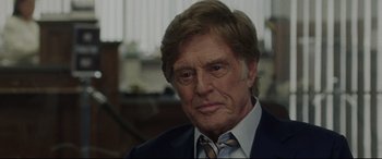 Movie still from “The Old Man & the Gun” (2018), directed by David Lowery – An older man in a suit and tie looking at the camera; Close Up shot, Over the shoulder angle