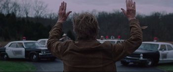 Movie still from “The Old Man & the Gun” (2018), directed by David Lowery – An older man with his hands up in the air; Medium shot, Low angle
