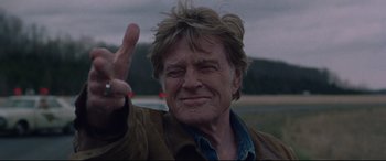 Movie still from “The Old Man & the Gun” (2018), directed by David Lowery – An older man giving the peace sign with his hand; Close Up shot, Low angle