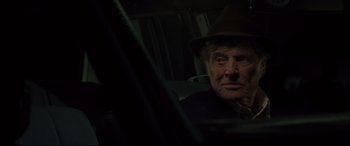 Movie still from “The Old Man & the Gun” (2018), directed by David Lowery – An older man wearing a hat sitting in a car; Close Up shot, Over the shoulder angle