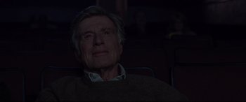 Movie still from “The Old Man & the Gun” (2018), directed by David Lowery – An older man sitting in a chair in front of a projector screen; Close Up shot, Low angle