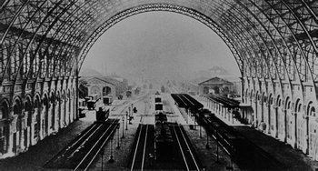 Movie still from “The Organizer” (1963), directed by Mario Monicelli – An old photo of a train station with trains on the tracks; Extreme Wide shot, Low angle