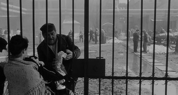 Movie still from “The Organizer” (1963), directed by Mario Monicelli – An old man sitting on a bike in front of a fence; Wide shot, High angle