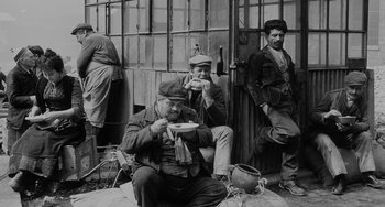 Movie still from “The Organizer” (1963), directed by Mario Monicelli – A group of men sitting next to each other eating food; Wide shot, High angle