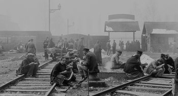 Movie still from “The Organizer” (1963), directed by Mario Monicelli – A black and white photo of a group of men sitting on train tracks; Wide shot, High angle