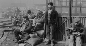 Movie still from “The Organizer” (1963), directed by Mario Monicelli – An old photo of a man standing in front of other men; Wide shot, High angle