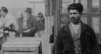 Movie still from “The Organizer” (1963), directed by Mario Monicelli – An old photo of a man standing in front of a building; Medium shot, Over the shoulder angle