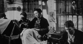 Movie still from “The Organizer” (1963), directed by Mario Monicelli – A woman sitting in a chair in a room with other women; Medium shot, Low angle